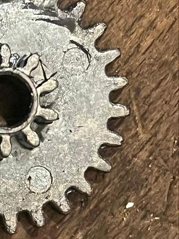 Versleten tandwiel uit een slot op een houten werkbank